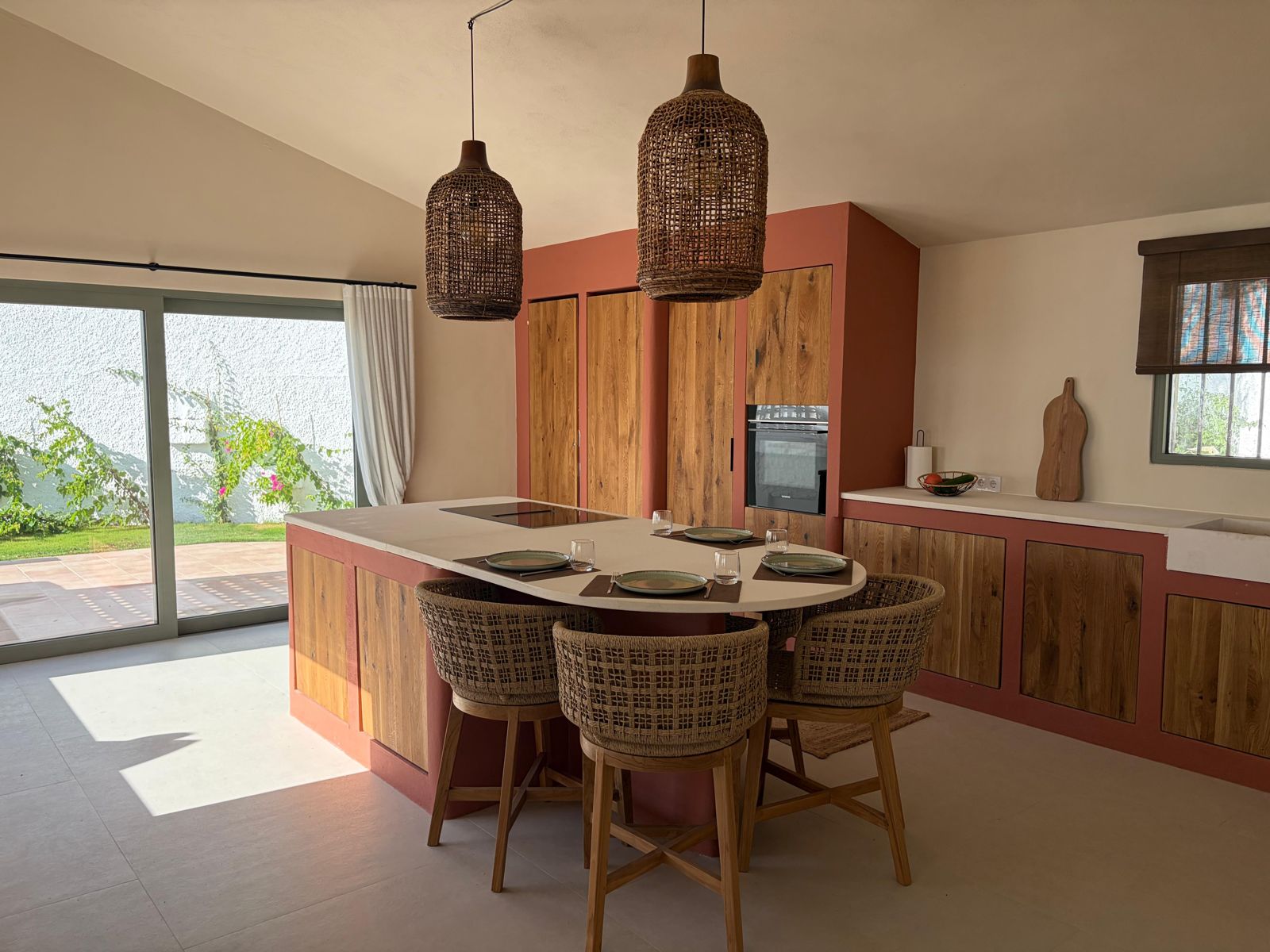 Open leefkeuken met eiland in terracotta en rieten hanglampen